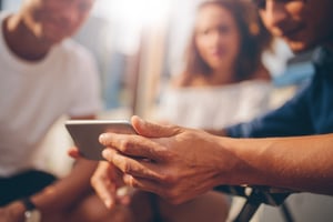 Man showing contents of his phone to a smiling group of friends